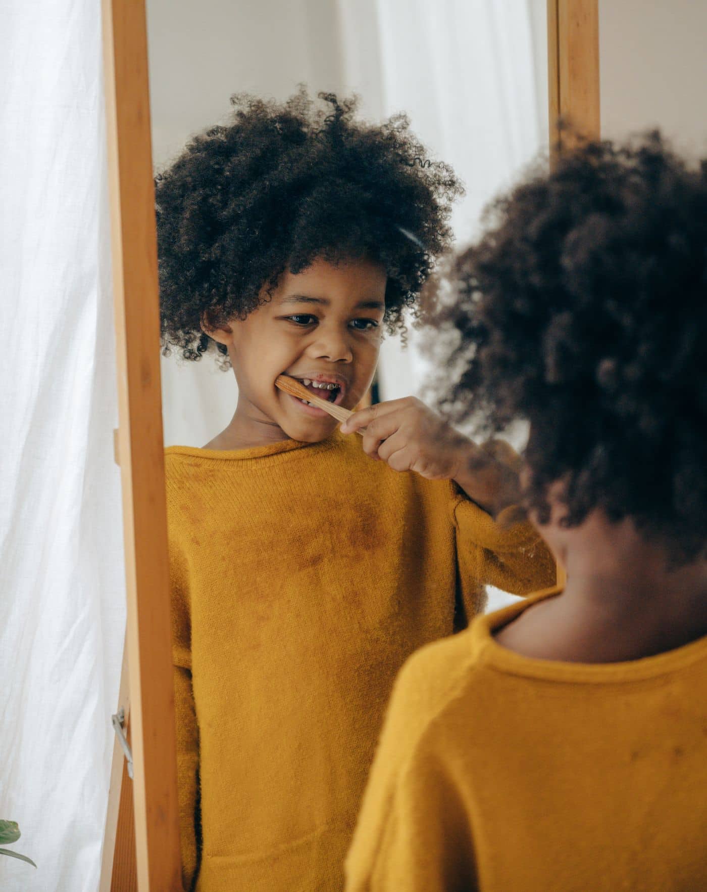 Child brushing teeth in front of a mirror