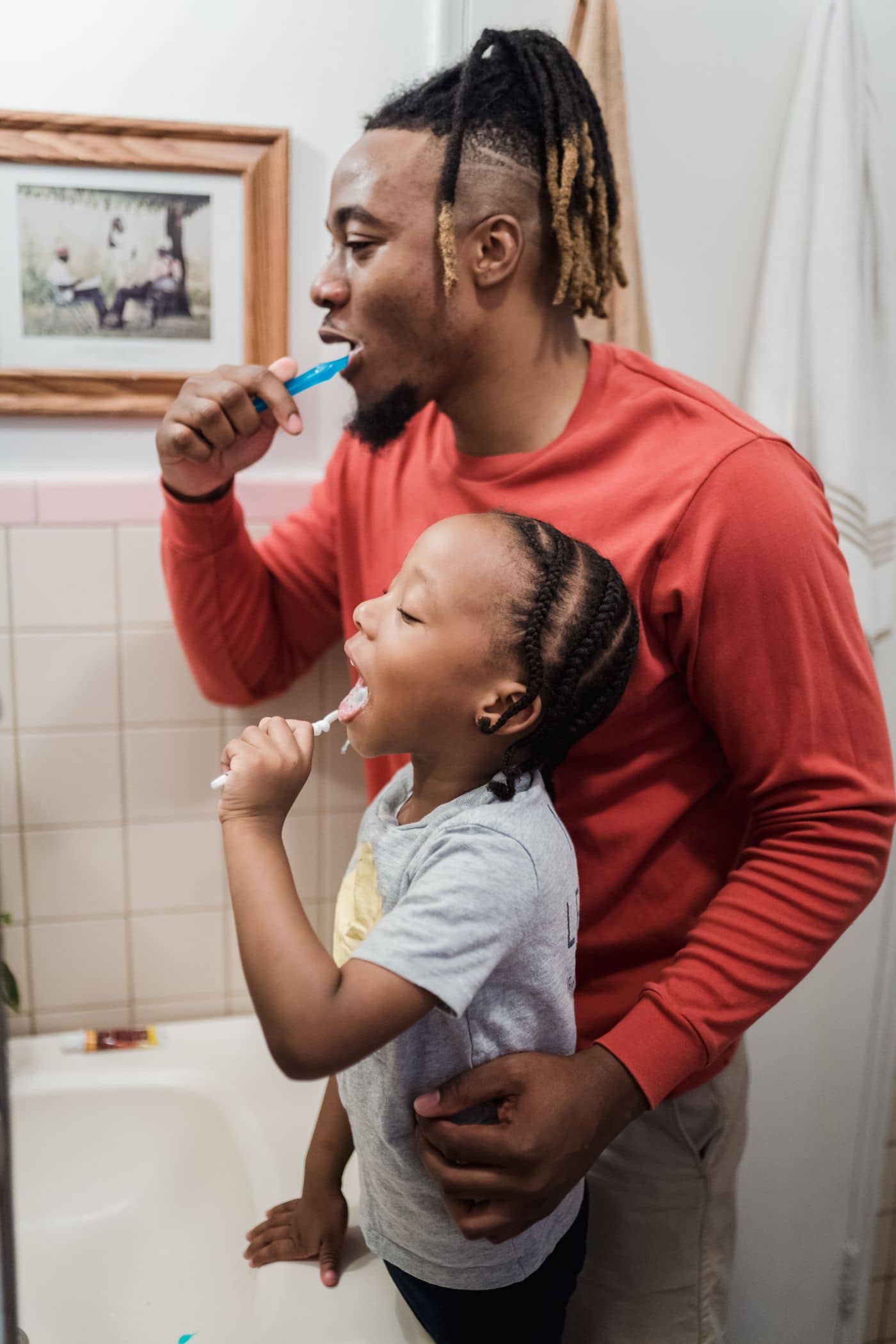 Father and daughter brushing teeth at the mirror