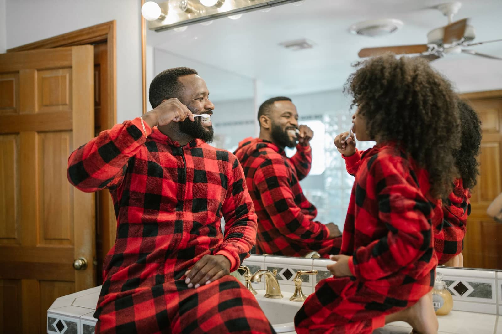 Father and daughter in matching pyjamas brushing teeth
