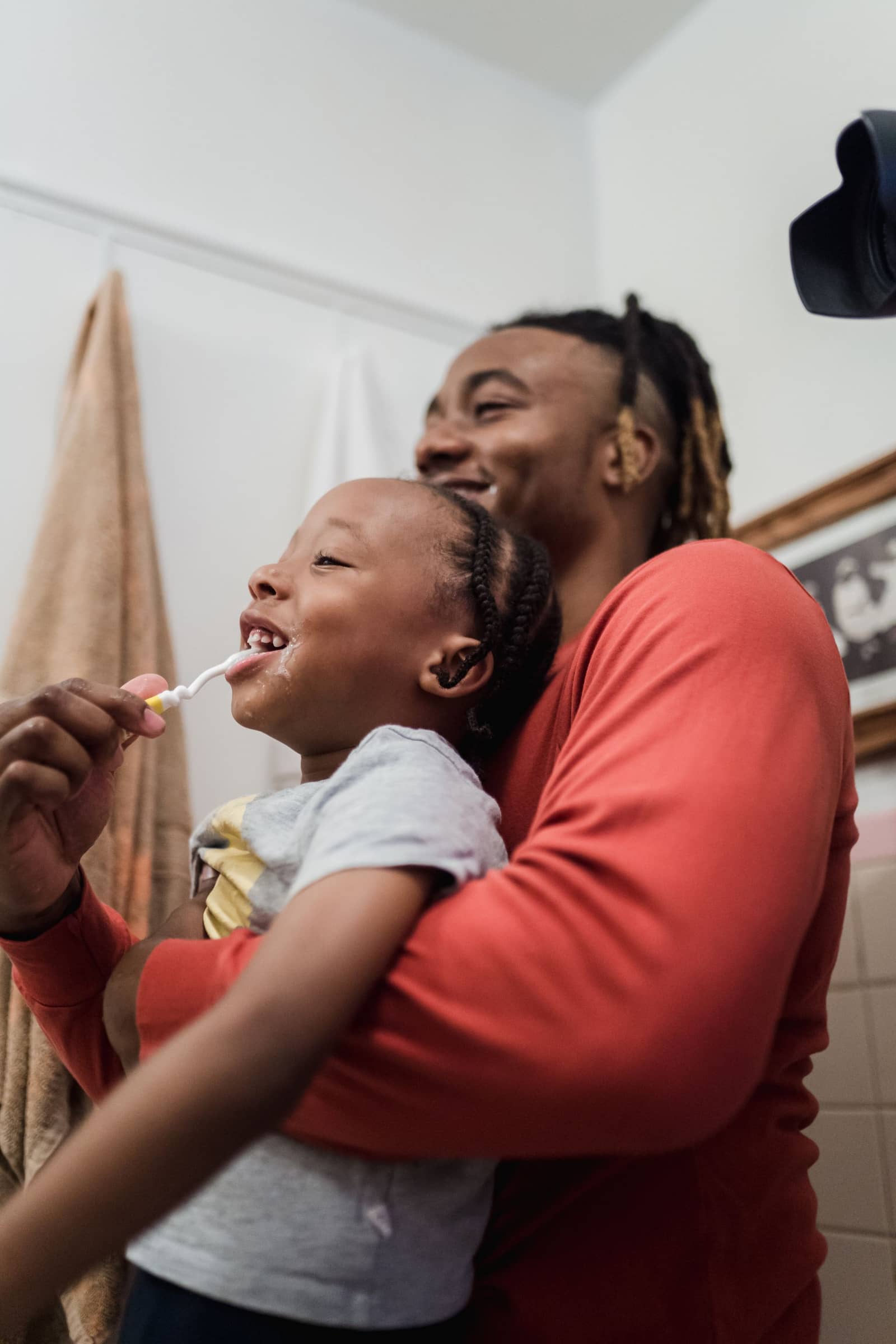 Father helping his son brush his teeth