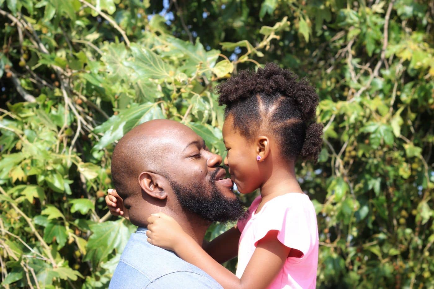 Father and daughter touching noses outdoors