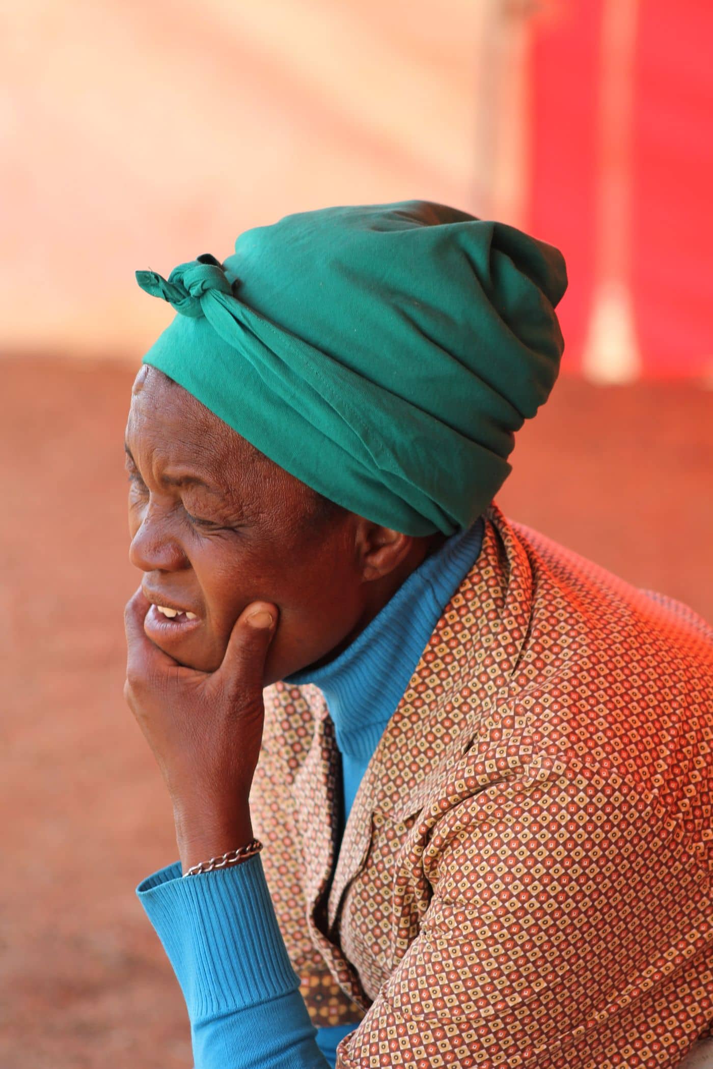 Older woman in a headscarf holding her jaw because of a toothache